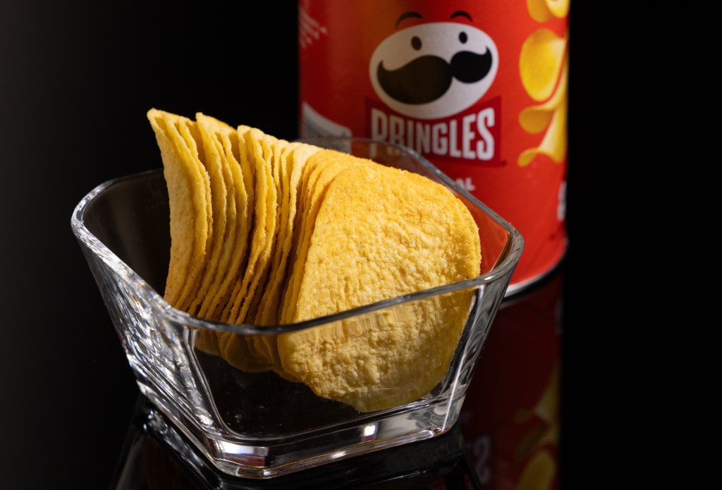 A glass bowl filled with Pringles chips, with a can of Pringles chips next to it, symbolizing Mars Inc.'s purchase of Kellanova.